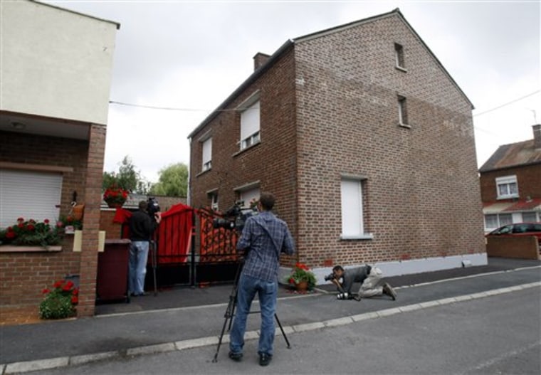 Reporters are seen in front of the house where French police found the corpses of eight newborn babies, in Villers-au-Tertre, northern France, Thursday, July 29, 2010. A judicial official said they have detained the parents of the dead babies, both in their mid-40s, and that the corpses were found on two different parts of their property.(AP Photo/Remy de la Mauviniere)